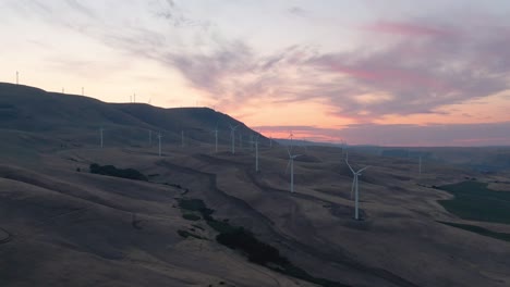 beautiful aerial landscape view of wind turbines on a windy hill during a colorful sunrise