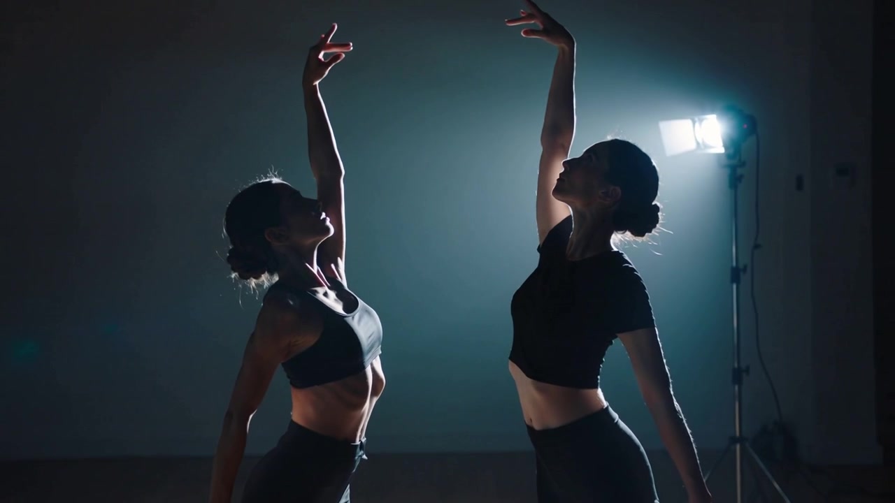 Reaching left dancer and partner in sportswear making contact in studio starting duet with lamp