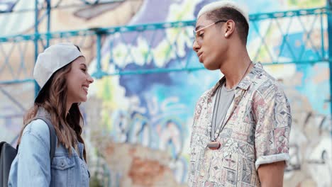 caucasian smiling woman in hipster style wearing cap and talking with her boyfriend in the street