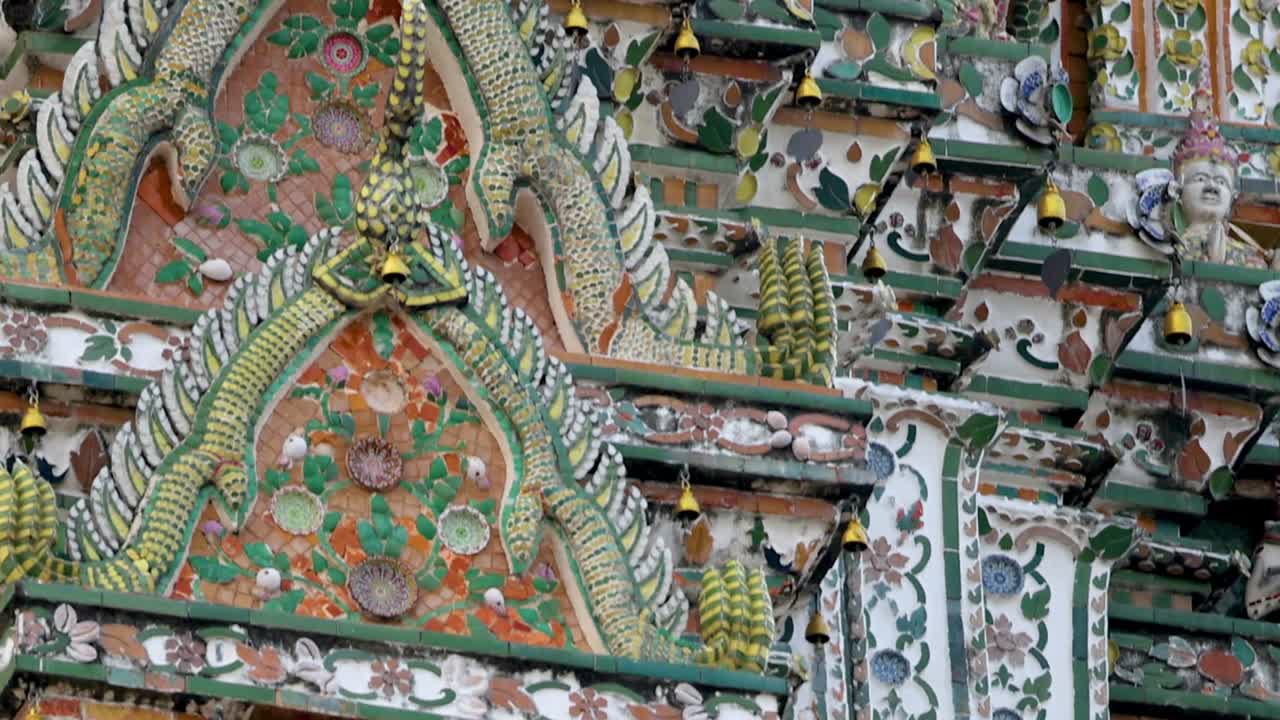 Detailed view of Wat Arun's intricate sculptures and colorful mosaic patterns showcasing traditional Thai craftsmanship.