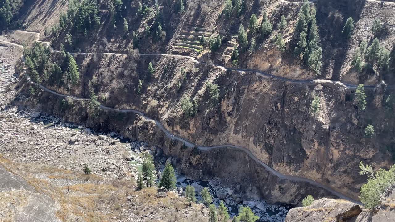 vista panorámica de una carretera de montaña con un automóvil solitario que viaja por el valle de spiti en himachal pradesh, india