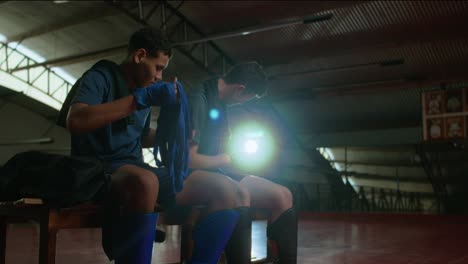 two young men prepare for martial arts training by wrapping their hands in a gym