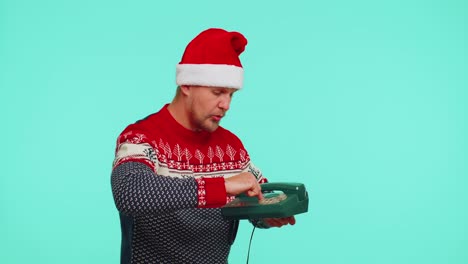 un hombre gracioso con un suéter navideño hablando por un teléfono antiguo con cable de los años 80, dice "oye, llámame de nuevo"