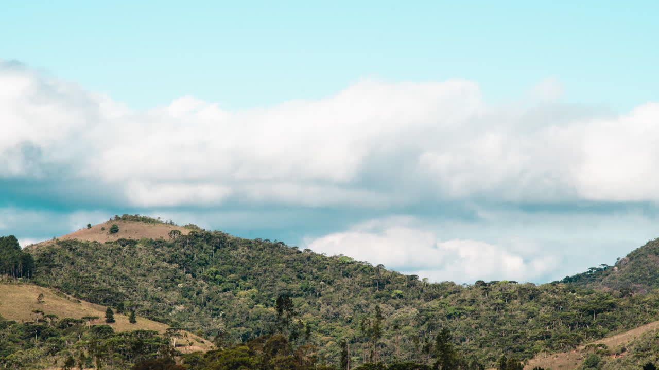 amplia toma de tiempo de nubes moviéndose en el cielo detrás de montañas verdes.