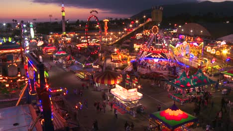 a high angle view over a brightly lit amusement park with many rides and attractions