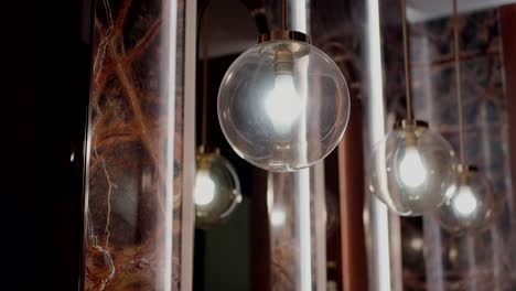 elegant glass globe pendant lights with glowing bulbs set against a polished marble backdrop