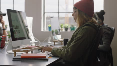 joven mujer de negocios caucásica usando computadora escribiendo información de proyectos navegando por la web buscando en línea lluvia de ideas trabajando en una oficina moderna