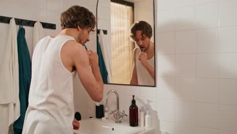 man brushing teeth in bathroom