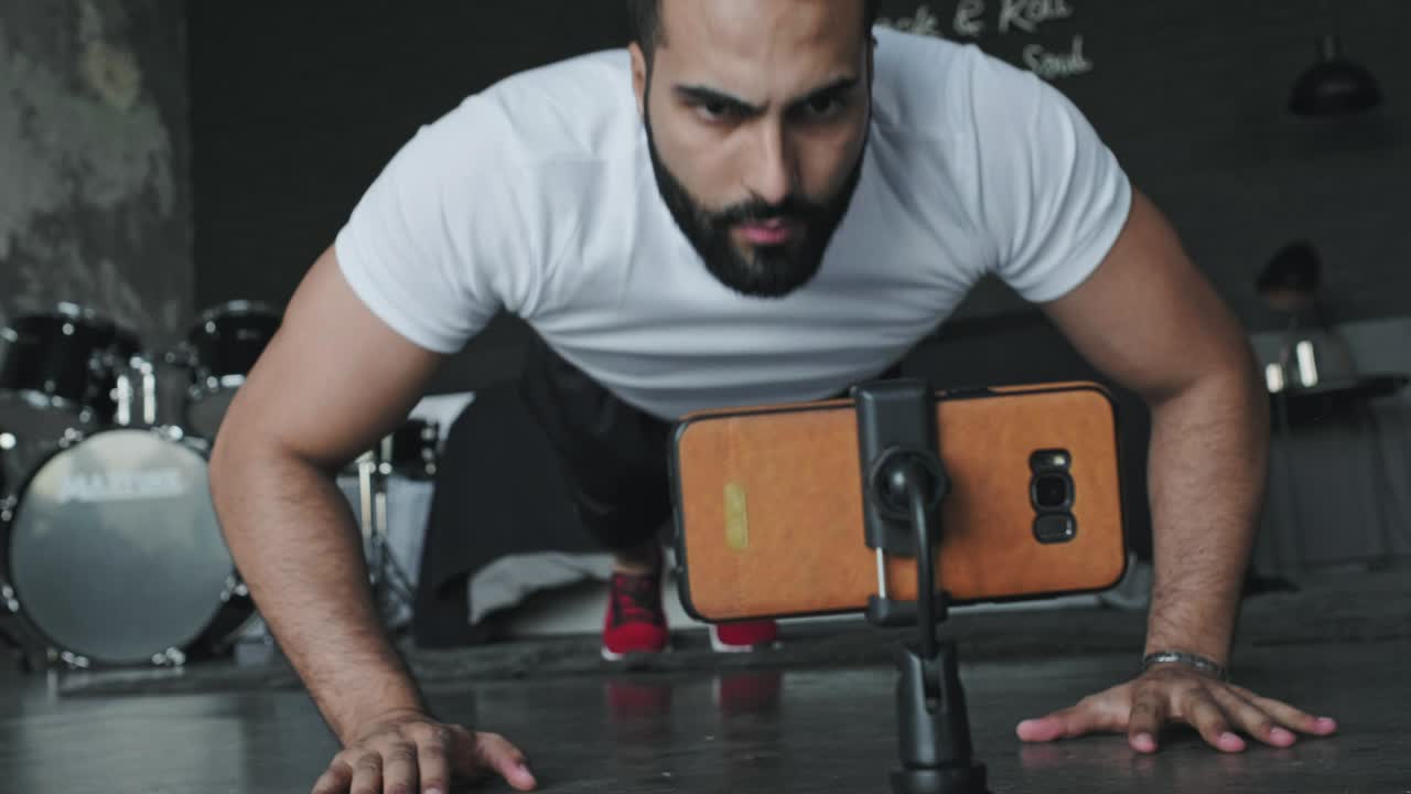 젊은이가 음악 스튜디오에서 연습을 하고 전화로 촬영합니다.