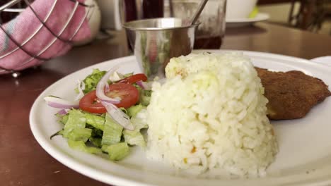 a plate with rice, fresh salad with tomatoes, onions, and lettuce