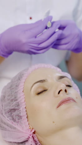 a specialist is making injections of mesotherapy to a client in the forehead area in the center of cosmetology. modern cosmetology. skin moisturizing procedure vertical video