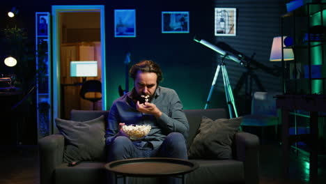 man in apartment chocking on popcorn while watching movie on tv