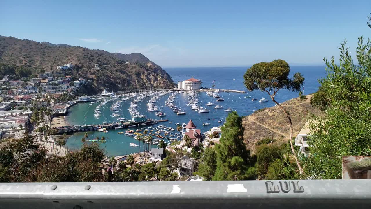 정박한 보트가 있는 항구의 바다 전망을 보기 위해 측면을 바라보며 절벽 길을 운전하다