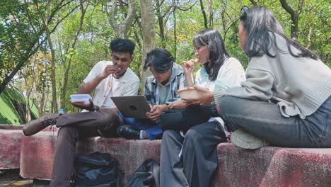 four asian college students learning and eating lunch together at campus park