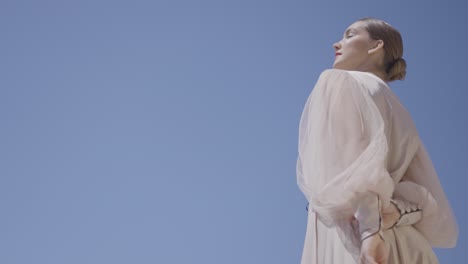 woman in beige dress against a clear sky