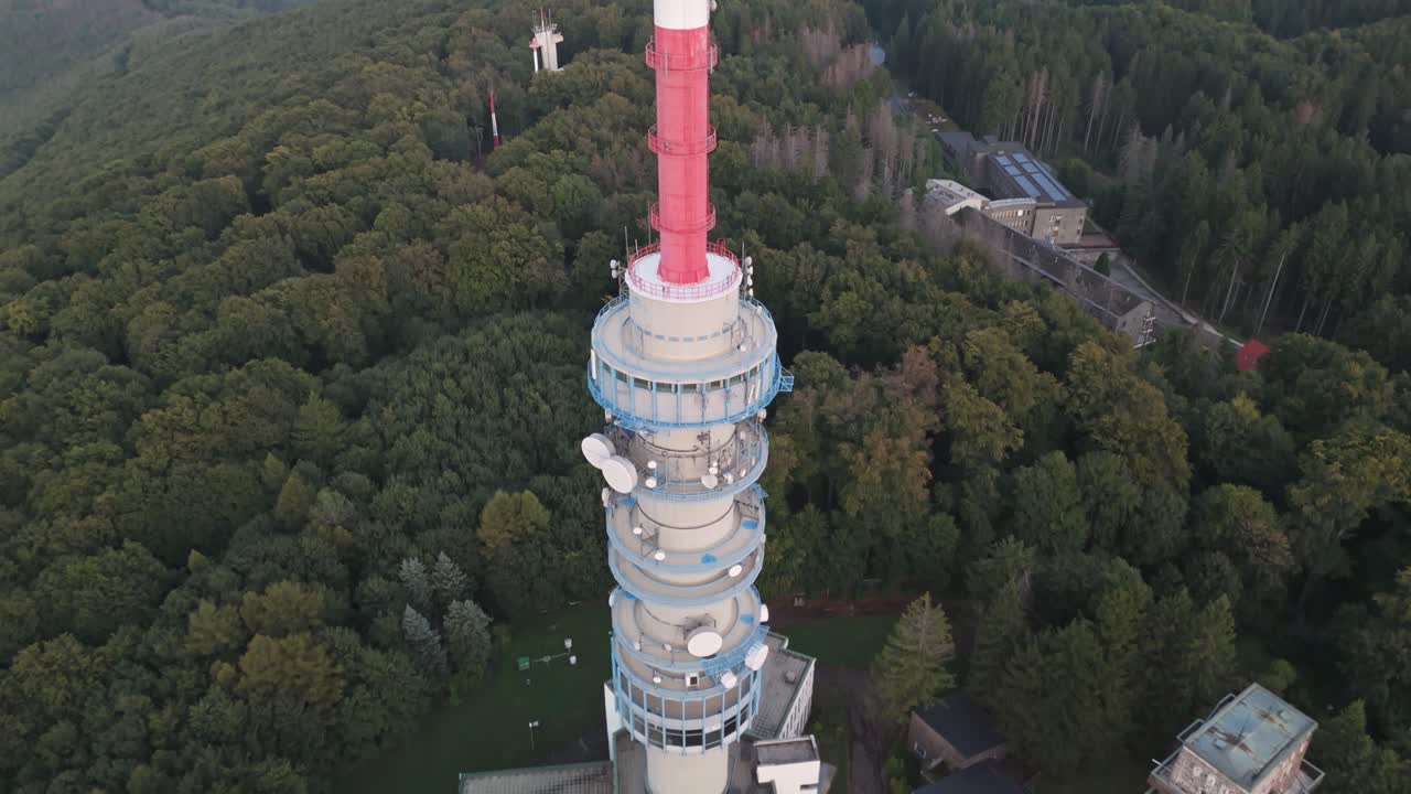 Tilt-down drone view from the Kékestető TV Tower from the top through the directional microwave antennas to the base facility building in Hungary