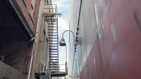 external fire escape stair case attached to old building in grand lane, perth, western australia with an old lamp and street art graffiti on the wall