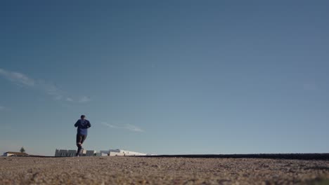 runner running road, low angle back view, blue sky and empty roadway, healthy lifestyle