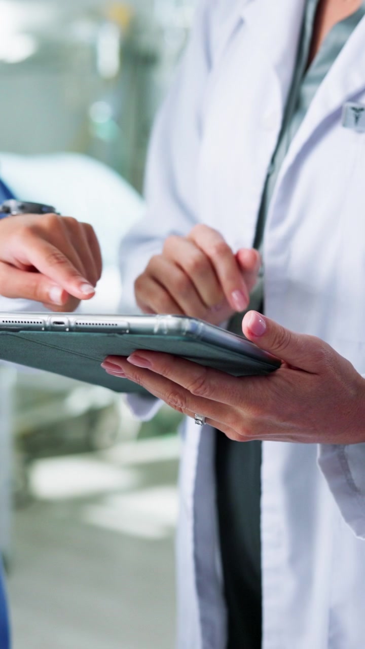 Sundhedspersonale gennemgår patientdata på digital tablet på hospital