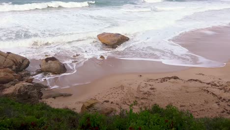 video of sea waves crashing into a majestic natural rock formation on the coastline