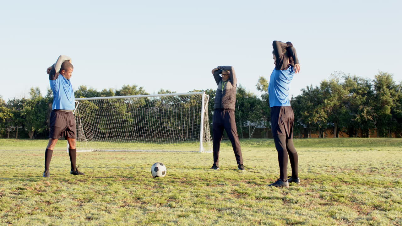Stretching before soccer practice, players warming up on field near goal