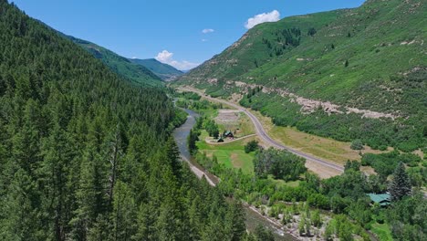 Aerial-over-a-forested-valley-with-a-road-through-the-middle-near-the-Crested-Butte-mountain,-Colorado,-USA