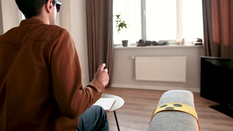 back view of a blind man sitting on the sofa, taking glasses off and reading a braille book