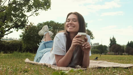 woman with paper cup lying on lawn