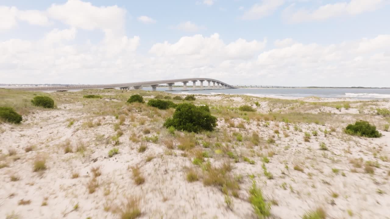 Drone shot of sand dunes with the bridge and ocean in the background