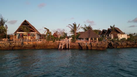 Tourists-at-beach-bungalow-resort-near-the-Indian-Ocean,-Aerial-pan-right-shot