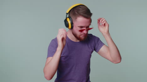 cheerful attractive man listening music via headphones and dancing disco fooling around having fun