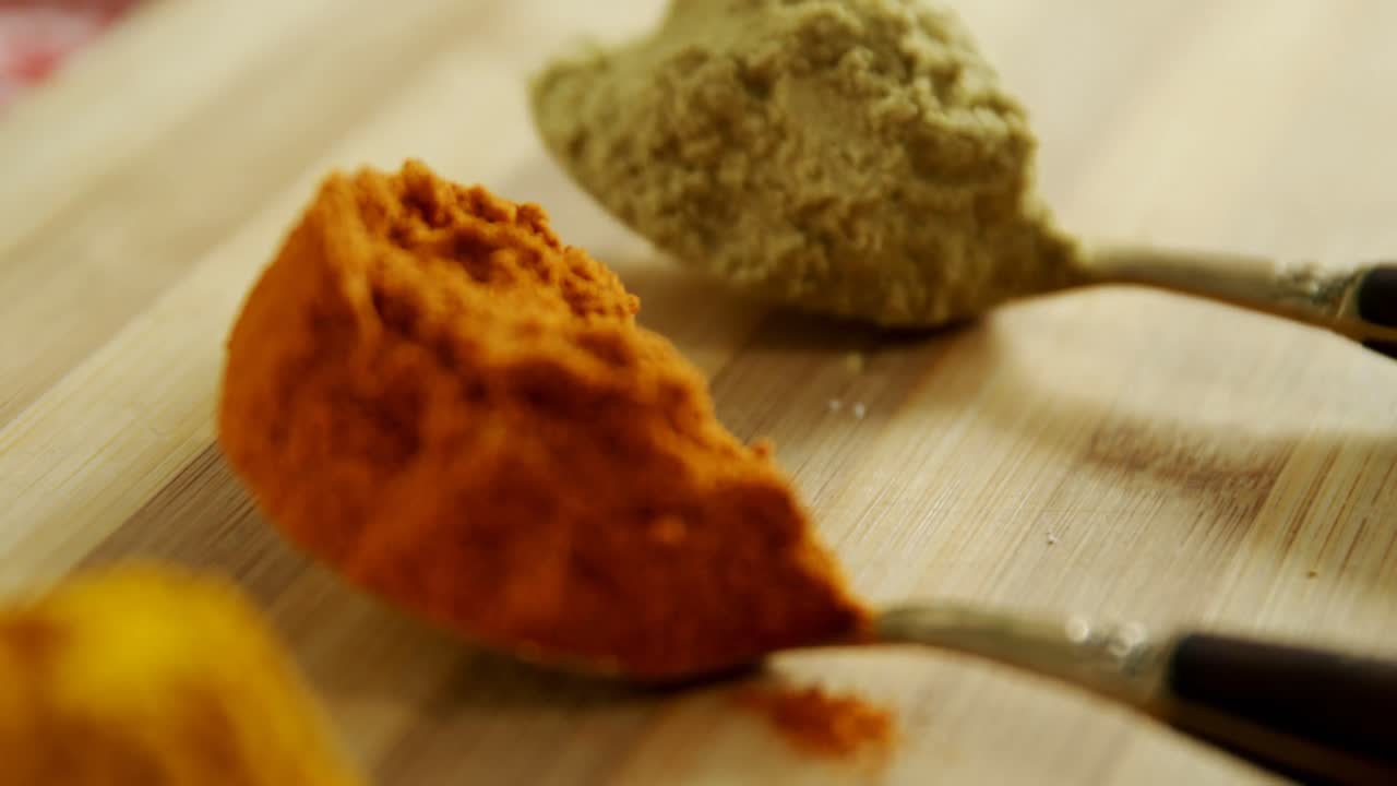 Turmeric powder, ed chili powder and coriander powder on a wooden table 4k