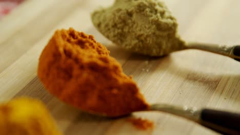 polvo de cúrcuma, polvo de chile y polvo de cilantro en una mesa de madera 4k