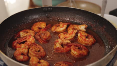 delicious meal preparation, peeled shrimps cooking in low heat on a shallow frying pan, slowly coating and absorbing the tasty flavoursome sweet paprika sauce