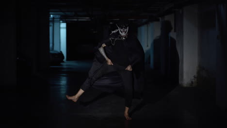 Creepy-scary-man-in-skeleton-Halloween-makeup-dancing-against-dark-parking-hallway-in-slow-motion