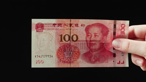 Hand Holding a 100 Chinese Yuan Banknote