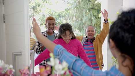 happy diverse group of teenage friends greeting and embracing at door at home, slow motion