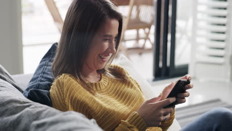 a young woman using a smartphone on the sofa