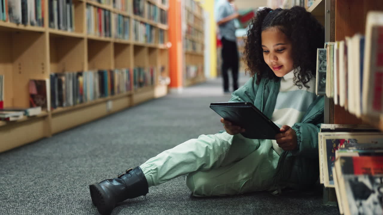 A young girl reading a tablet in the library