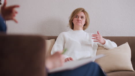emotional traveler seated comfortably on soft divan in quiet therapy room, lost in reflective moment while engaging in thoughtful session, warm cushions and relaxed posture add sense of introspection