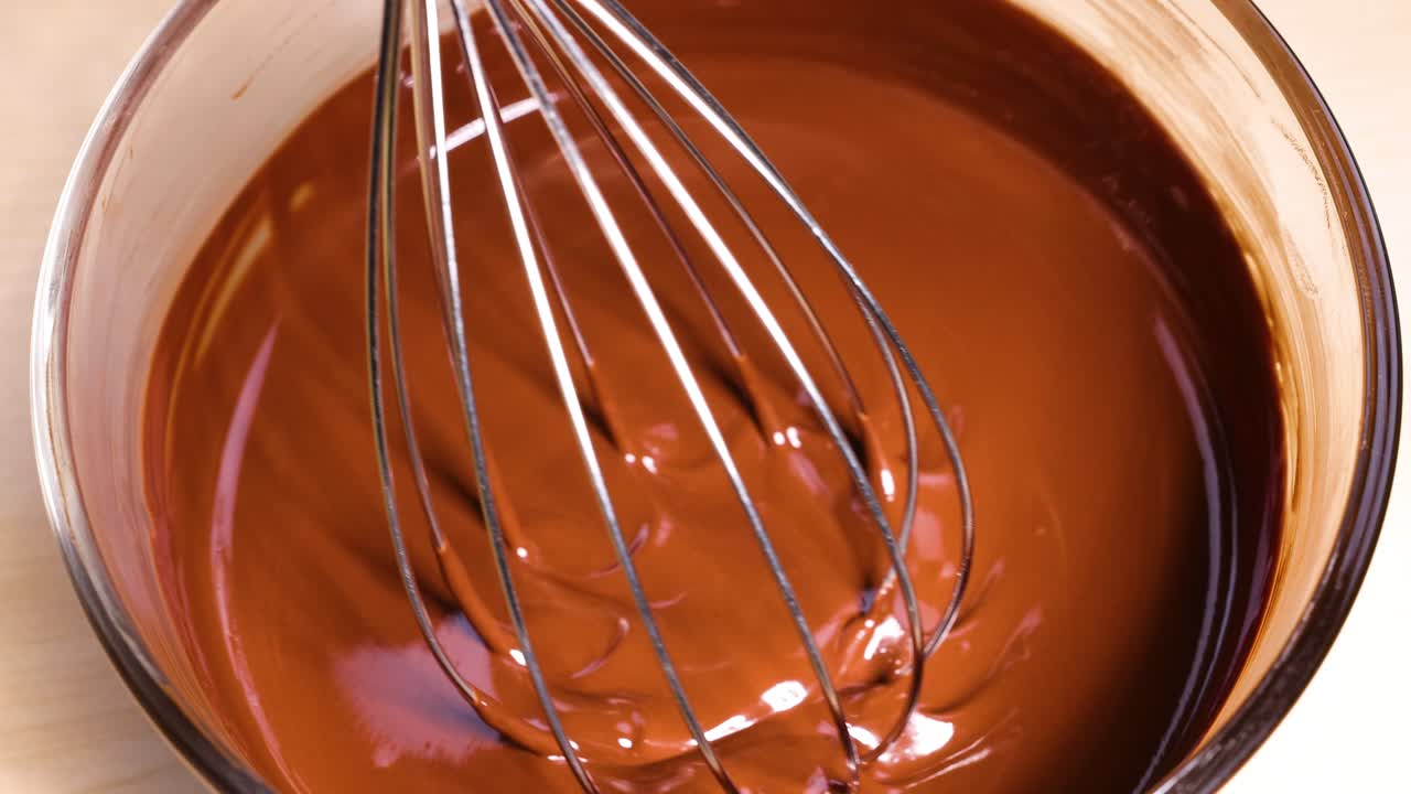 batir mezclando chocolate derretido en un tazón de vidrio