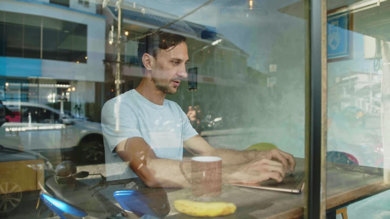 hombre trabajando en una computadora portátil en un café