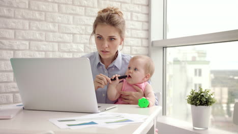 Working-mom-with-child-on-table.-Businesswoman-holding-toddler-girl-on-hand