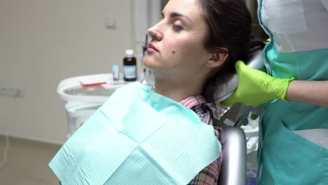 young female patient sitting on the dentist's chair and getting ready to check up. female doctor helping to feel comfortable. shot in 4k