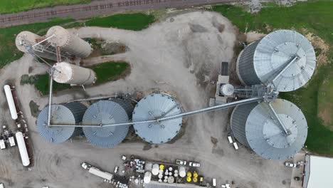 top down aerial shot of industrial silos and storage tanks with connecting machinery on a gravel site