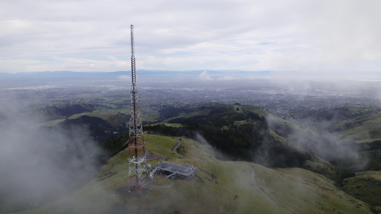 Aerial view passing the Sugarloaf mountain tower, misty day in New Zealand