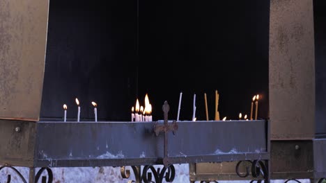 close up of candle flames burning in front of an orthodox christian church