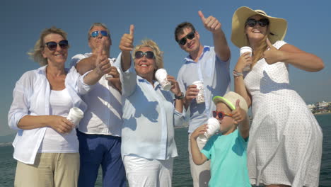 Happy-family-drinking-tea-and-showing-thumbs-up-outdoor