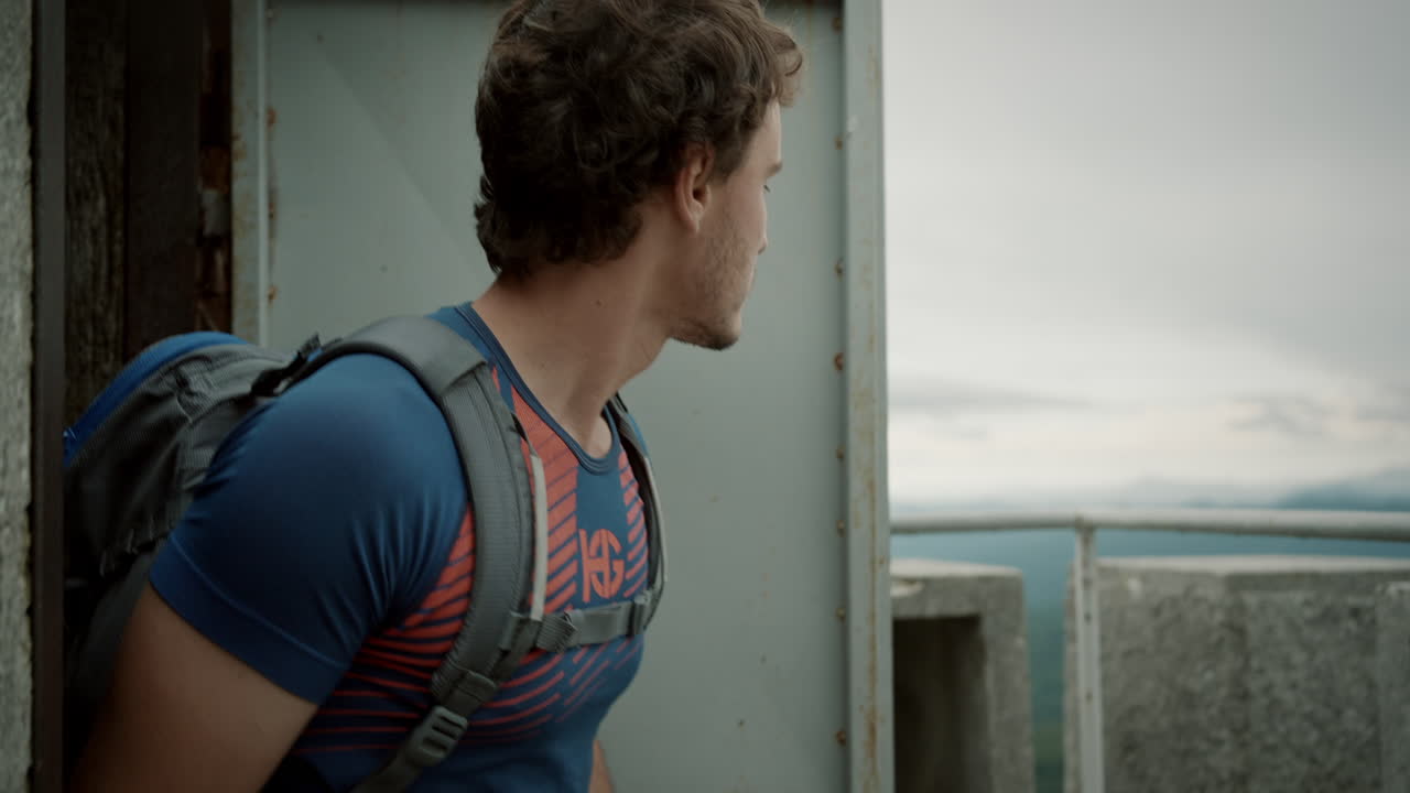 un joven excursionista entrando por la puerta en la parte superior de la torre para tener una vista