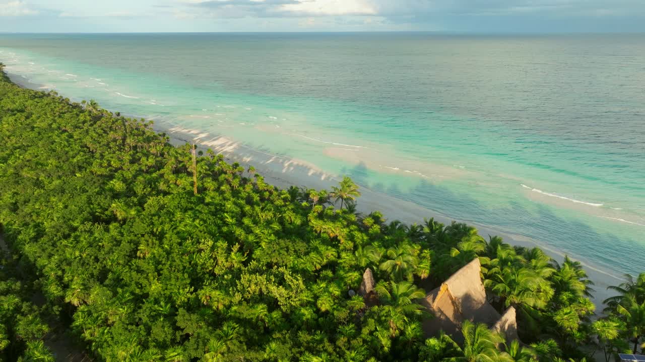 Aerial fly above hidden wood house inside a forest in Tulum beach, tropical Caribbean coastline
